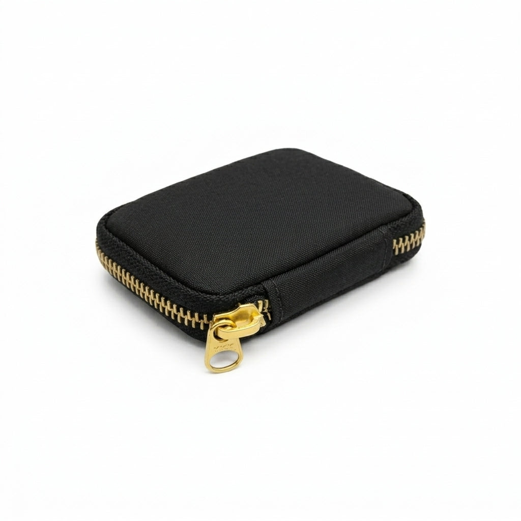 Compact black Cordura EDC pouch with gold zipper and pull tab, shown in angled front view on a clean white background